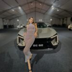 a woman posing in front of a car