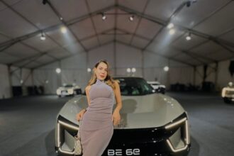 a woman posing in front of a car