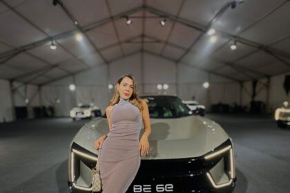 a woman posing in front of a car