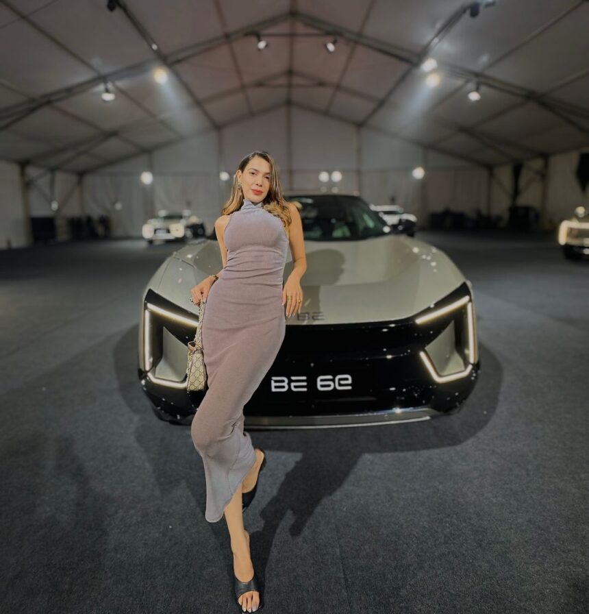 a woman posing in front of a car